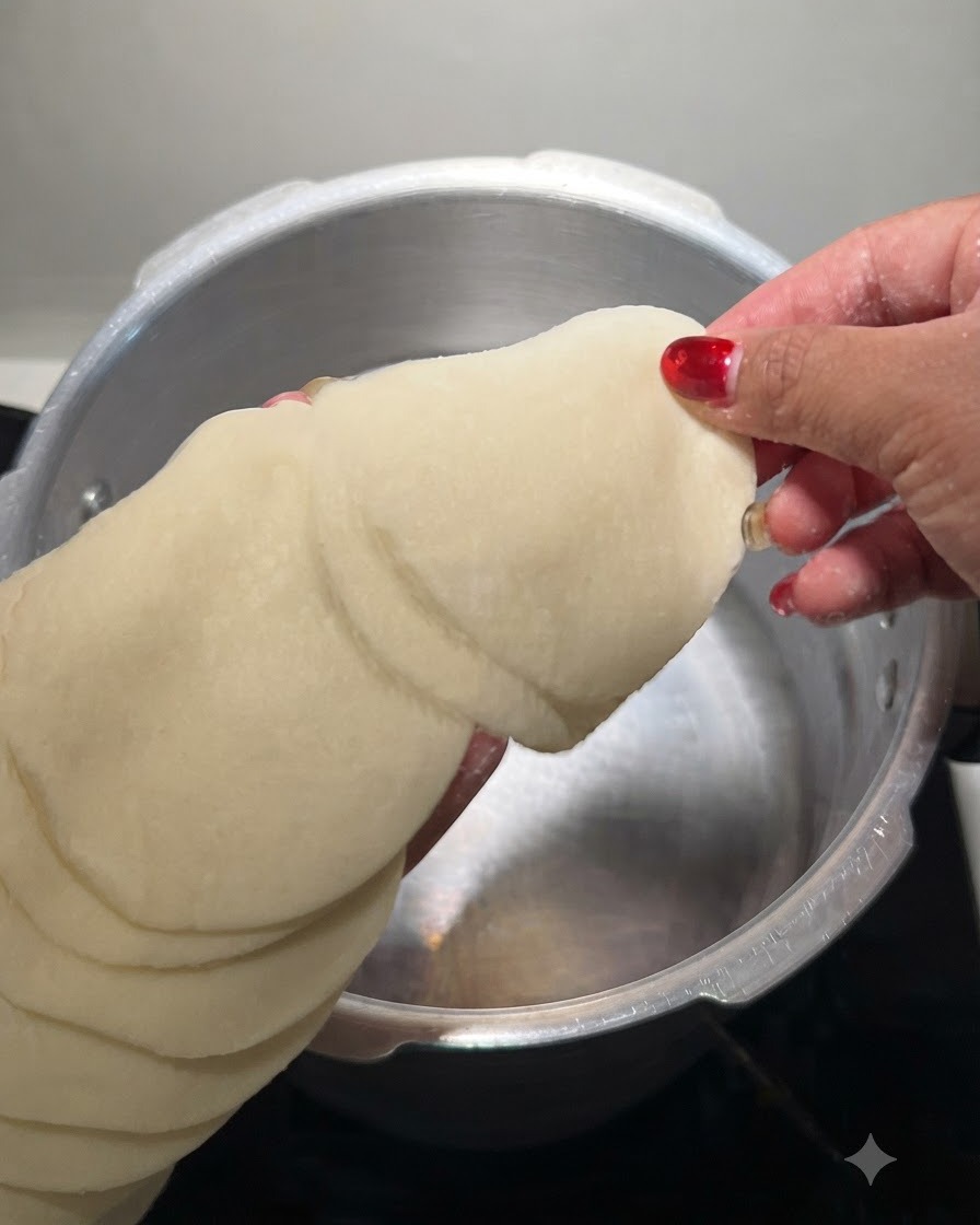 Una pila de obleas de dumpling redondas siendo sostenidas y sumergidas en una olla de metal con agua fría.