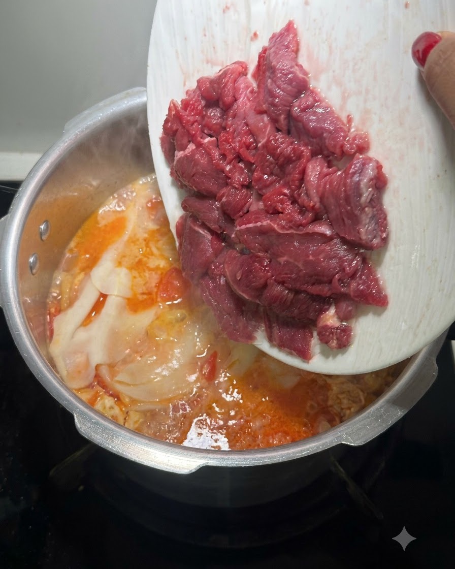 Rodajas frescas de carne de res roja cruda siendo volcadas desde un plato blanco en la olla de sopa hirviendo.