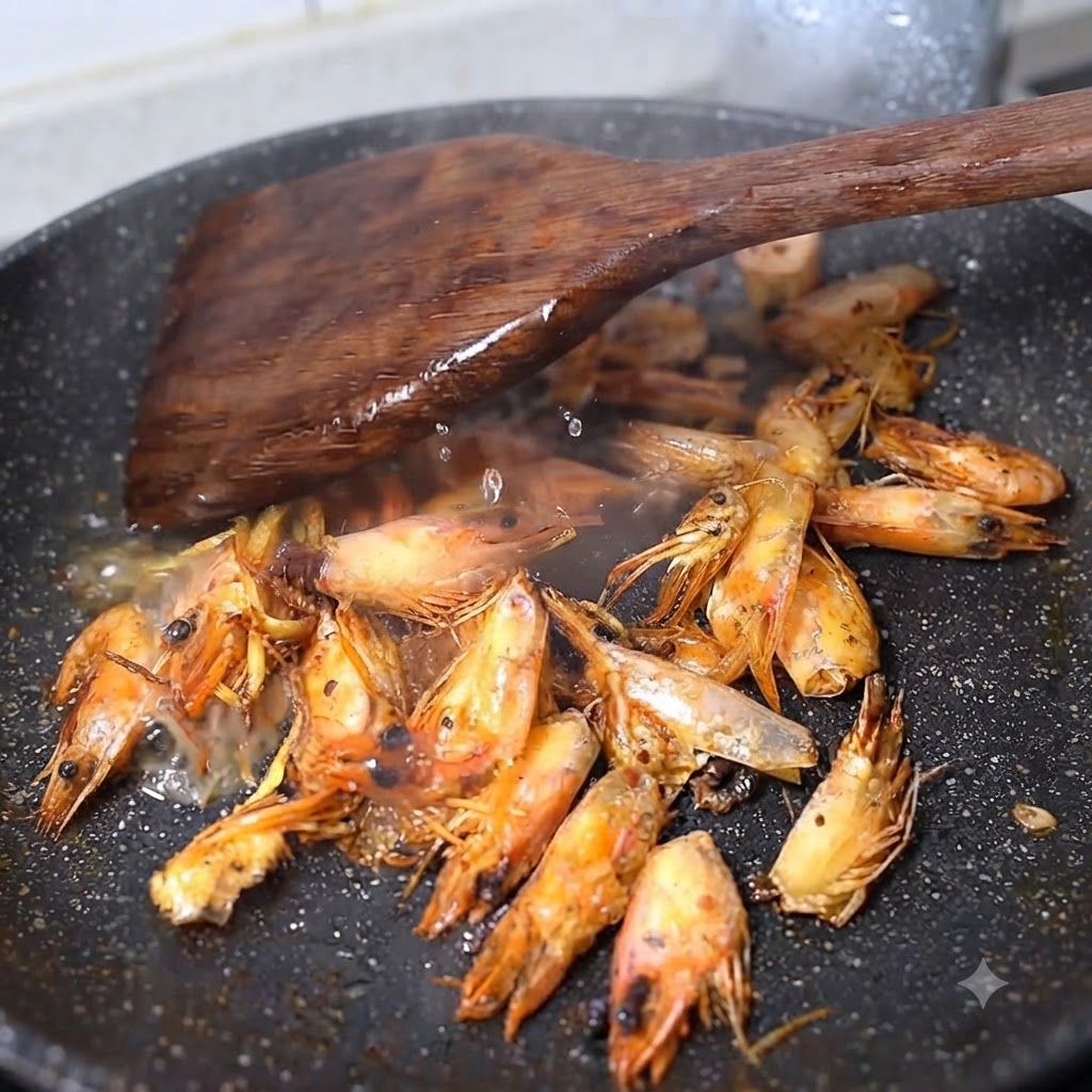 Agua caliente y vino para cocinar siendo vertidos sobre cabezas de camarón fritas en un wok, creando vapor y salpicaduras.
