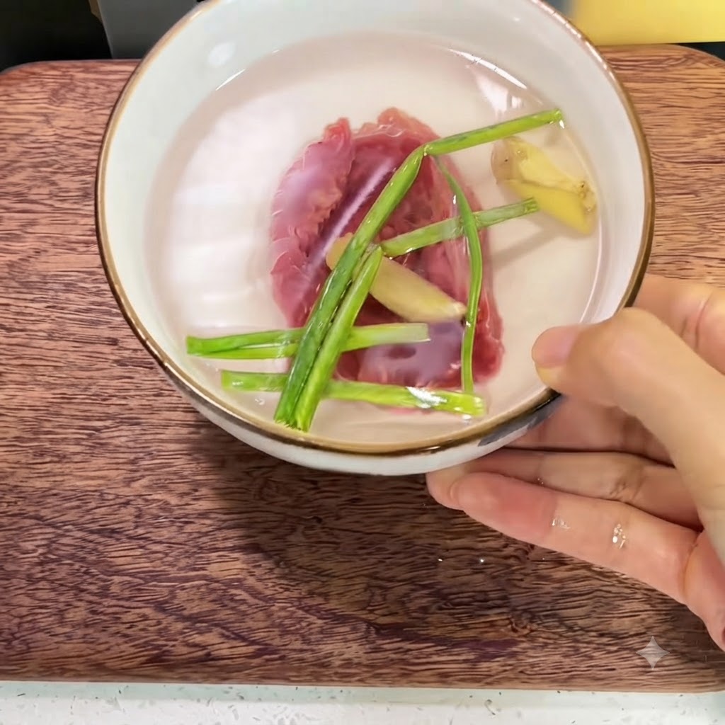 Ternera fresca en un tazón de cerámica lleno de agua con rodajas de jengibre y ramitas de cebolla verde.