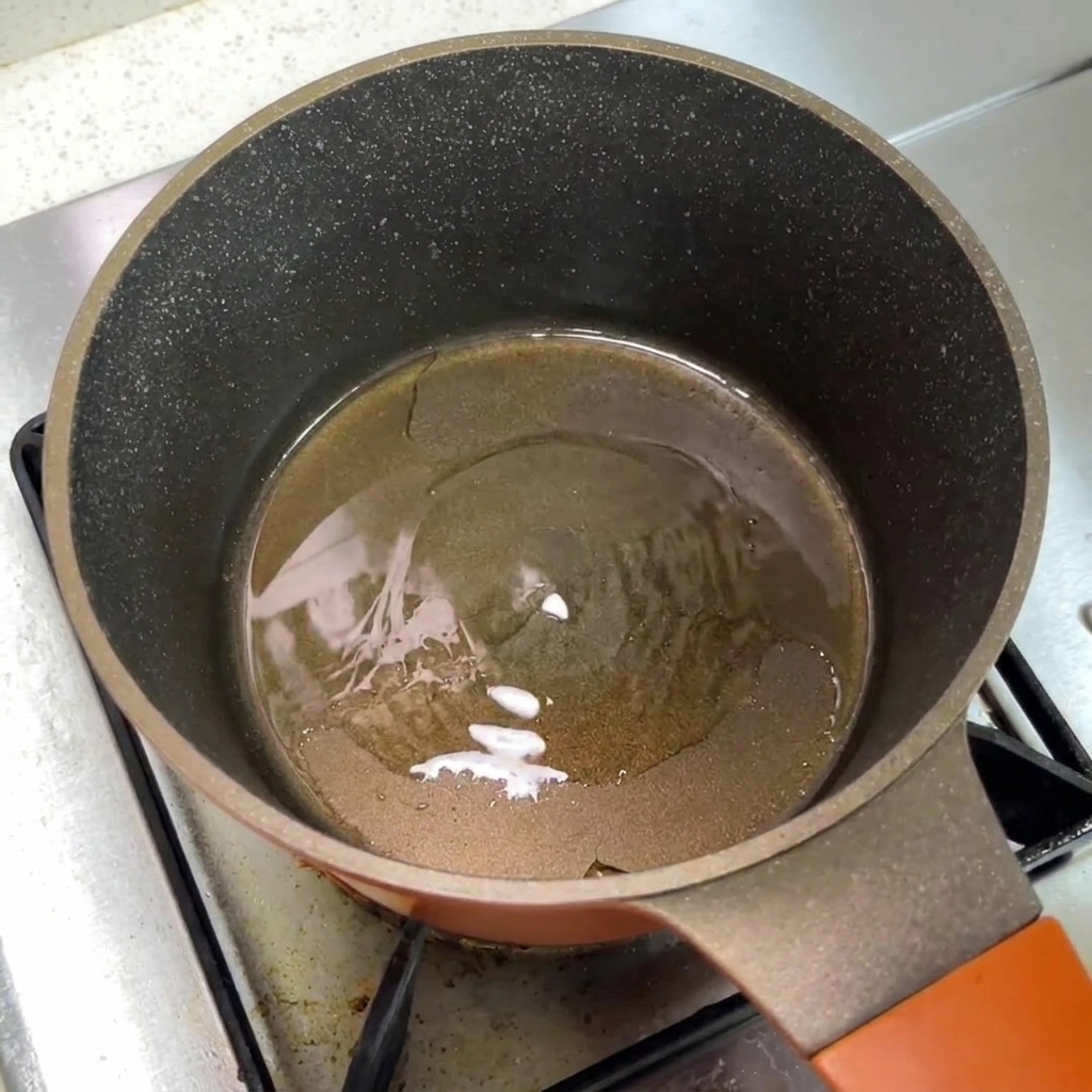 Una olla pequeña en la estufa que contiene aceite caliente.