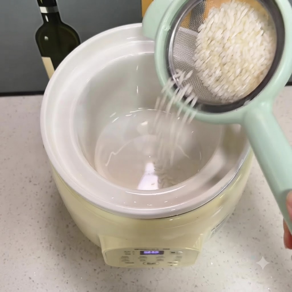 Arroz lavado cayendo desde un colador verde pequeño hacia la olla de cerámica blanca de la arrocera.
