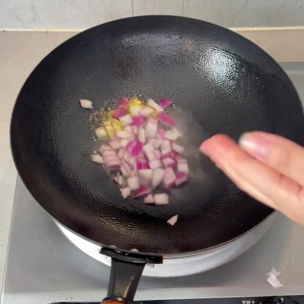 Cebollas rojas en dados chisporroteando en un wok negro con aceite caliente.