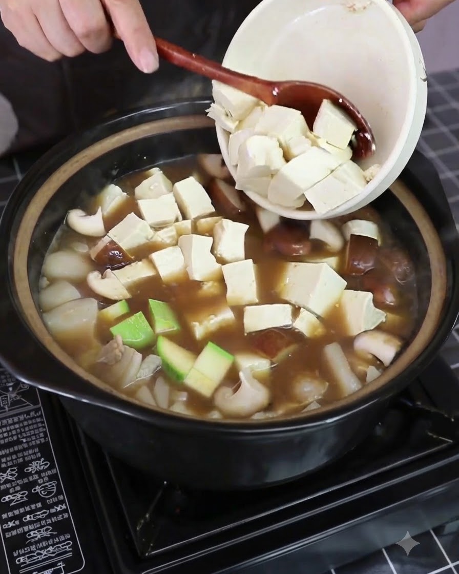 Trozo de col napa fresca siendo añadido a la olla hirviendo que contiene verduras y tofu.