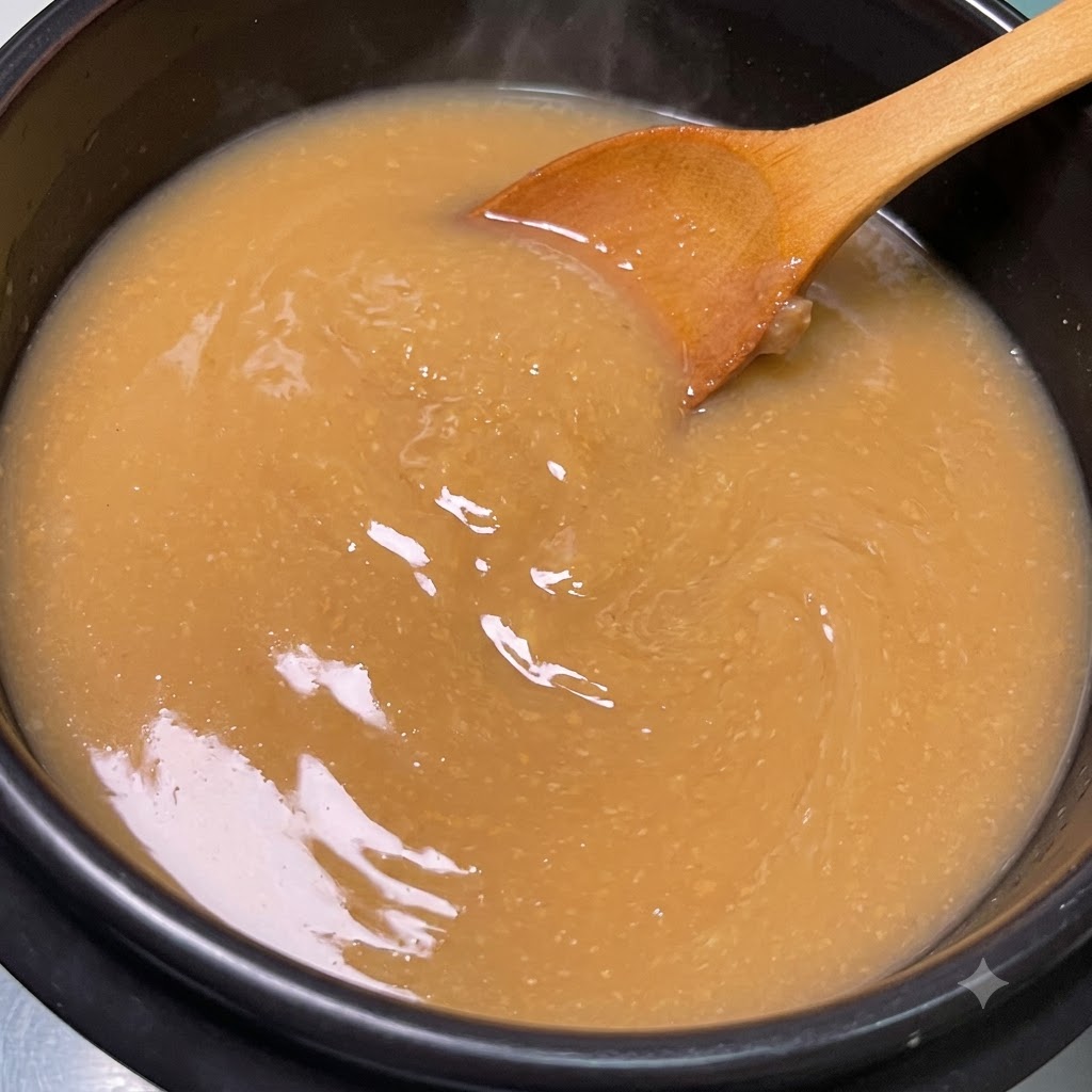 La cuchara de madera removiendo la mezcla de pasta de soja hasta que se disuelva por completo en el caldo hirviendo.