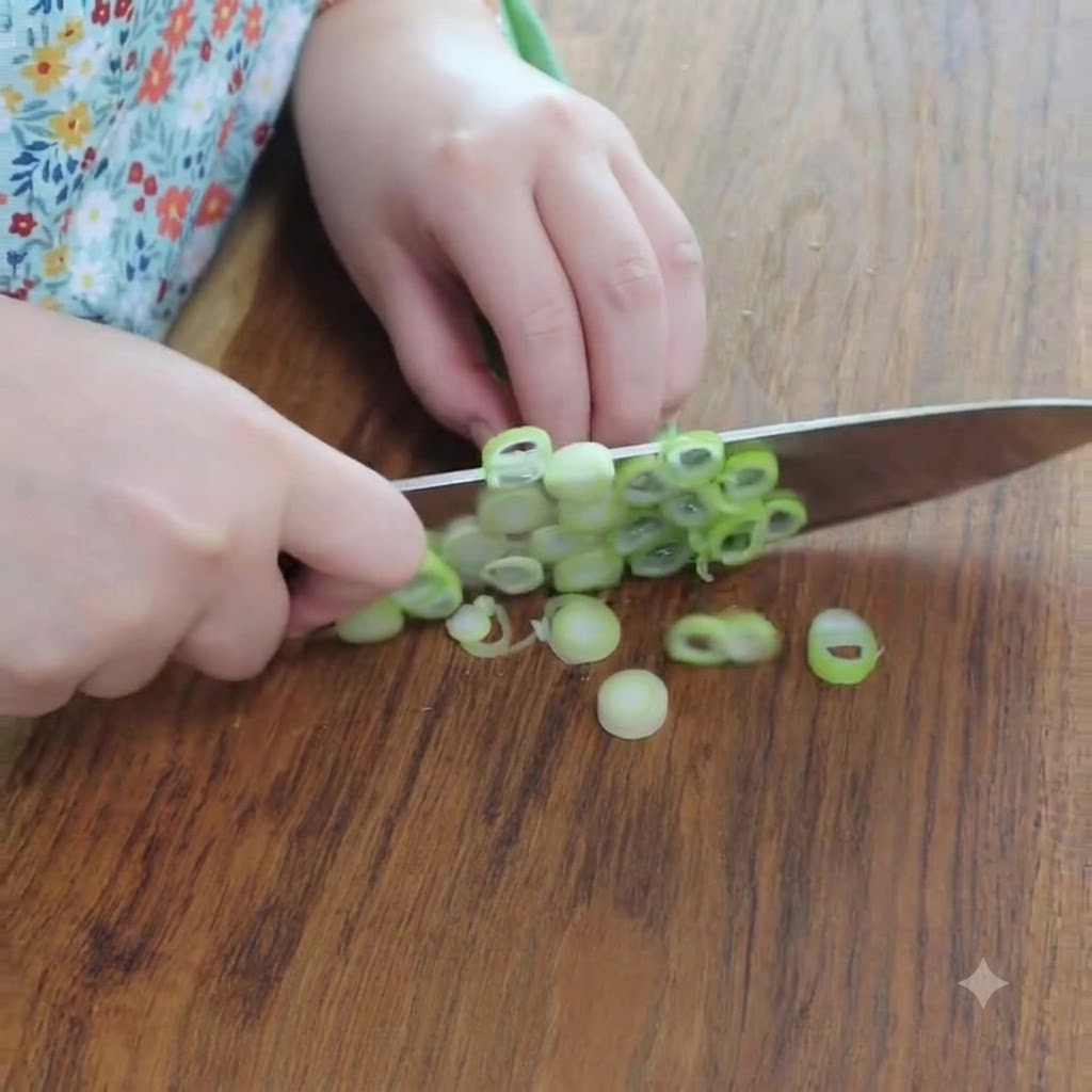Cebollas verdes frescas cortadas en aros pequeños sobre una tabla de cortar de madera usando un cuchillo de acero inoxidable.