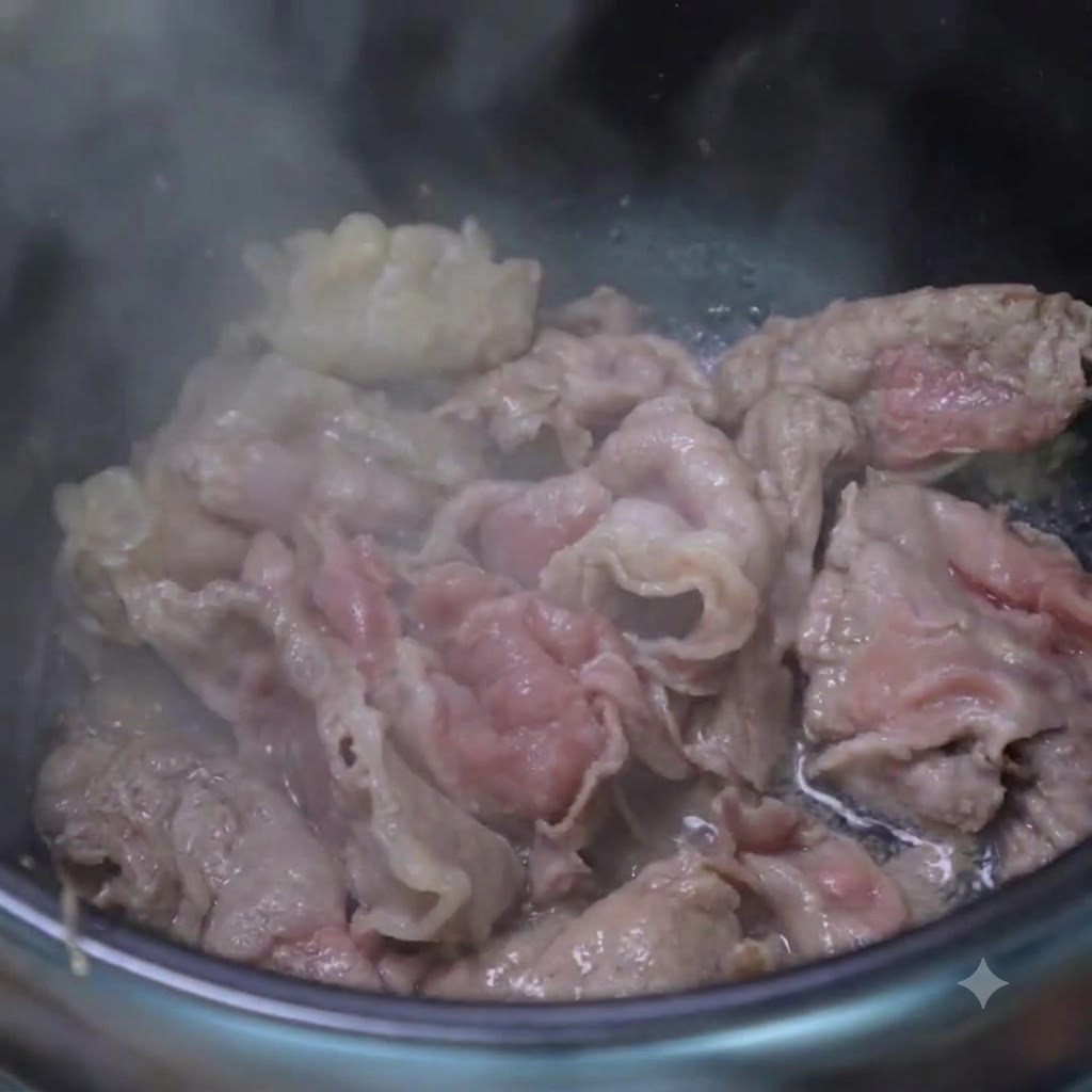 Una cucharada de ajo picado y cebollas verdes picadas salteándose con rodajas de carne cocida dentro de una olla de cocción.