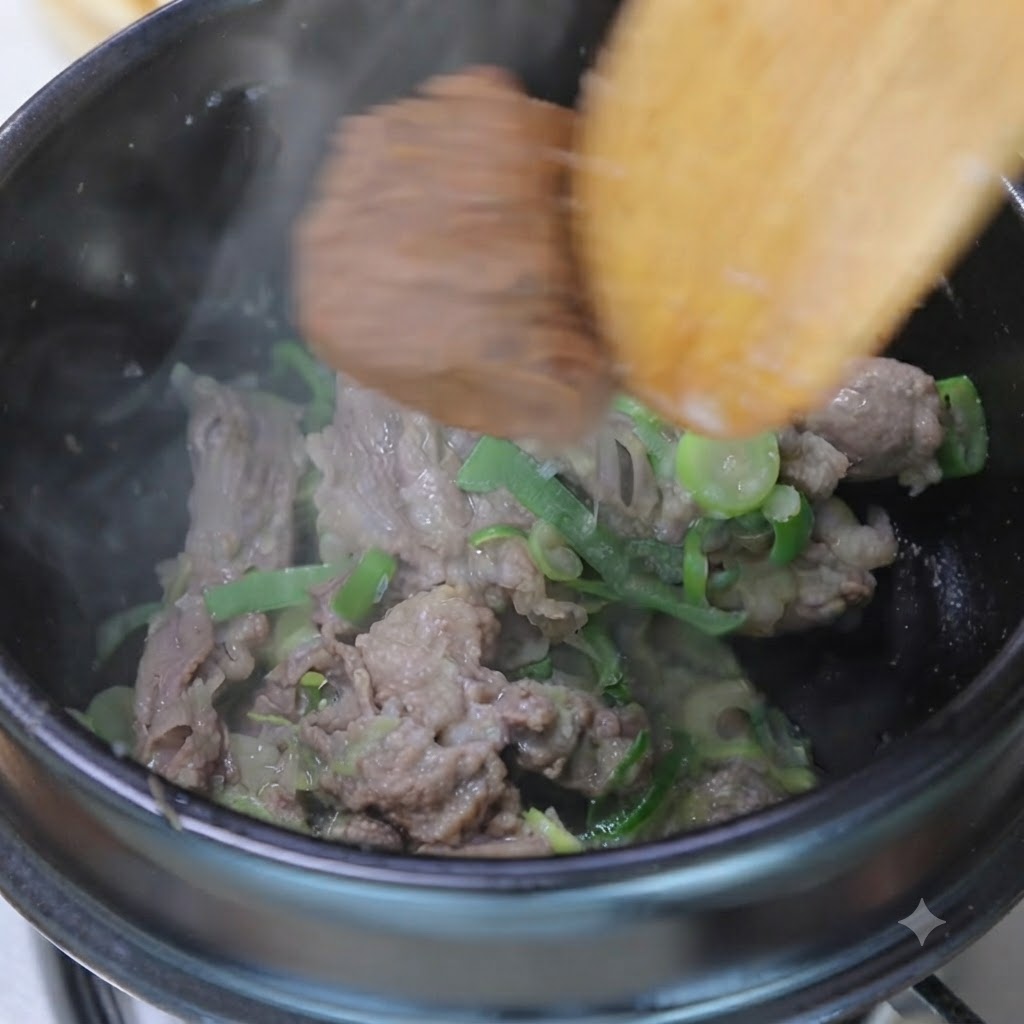 Una cucharada de pasta de soja y pasta de chile mezclándose con la carne salteada y los aromáticos dentro de una olla usando una espátula de madera.