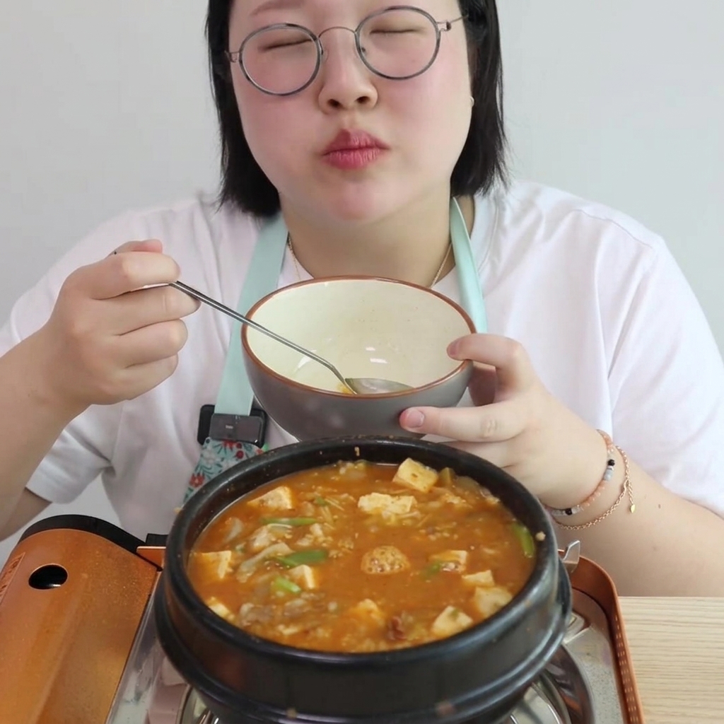 Una persona vertiendo agua en una olla de cocción llena de carne y pasta salteadas sazonadas, mientras sostiene un tazón para servir.