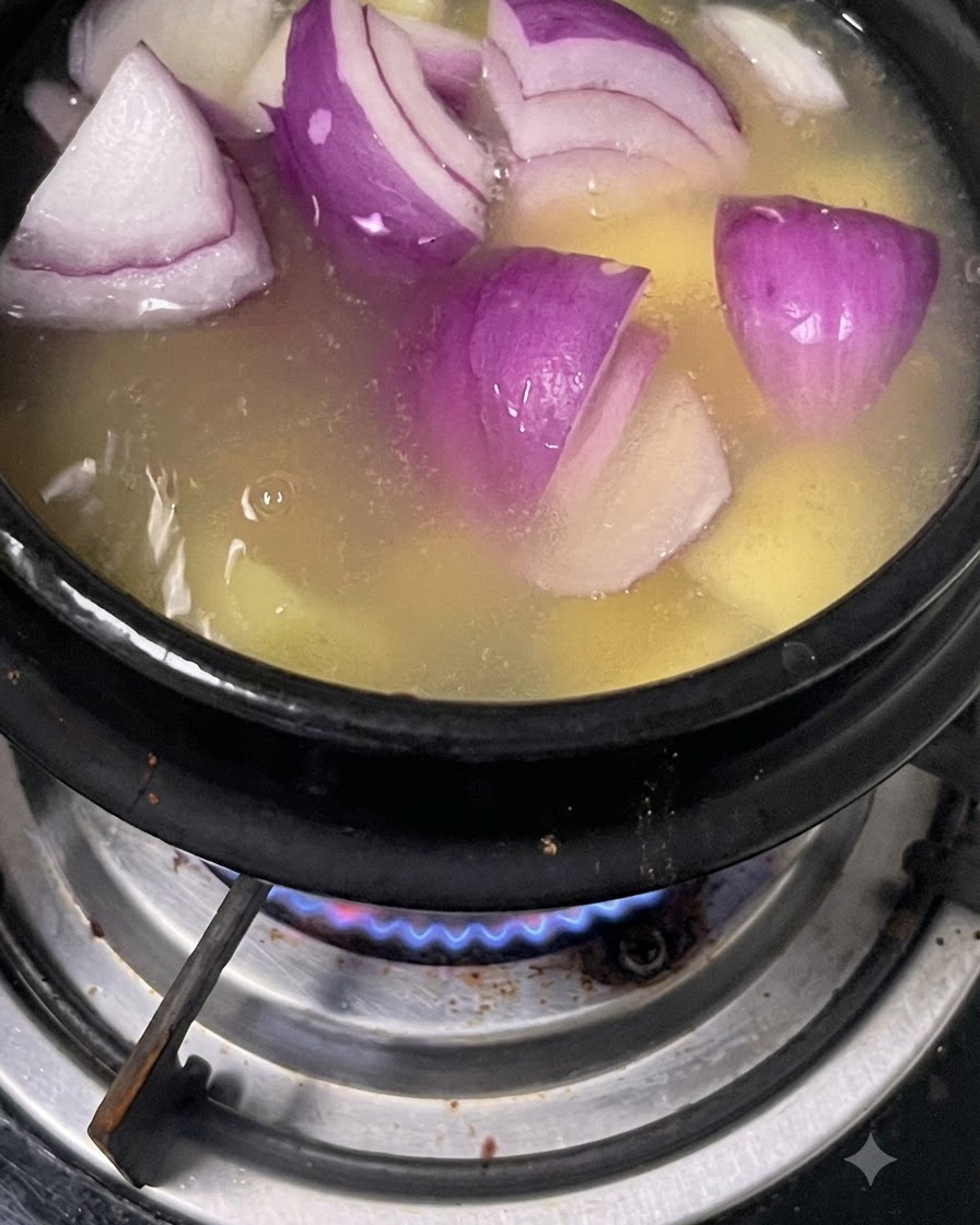 Cebollas moradas picadas flotando en la olla de caldo con patatas.