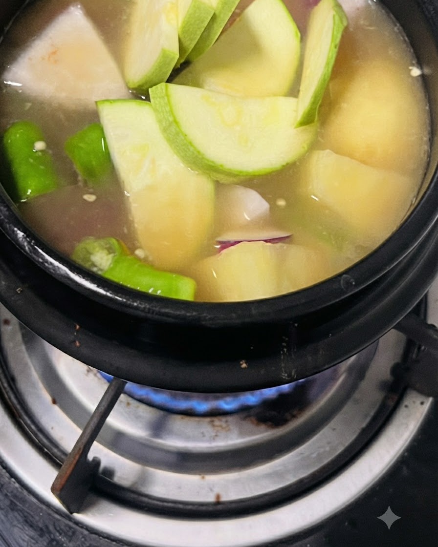 Calabacín en rodajas y chiles verdes añadidos a la olla de sopa.