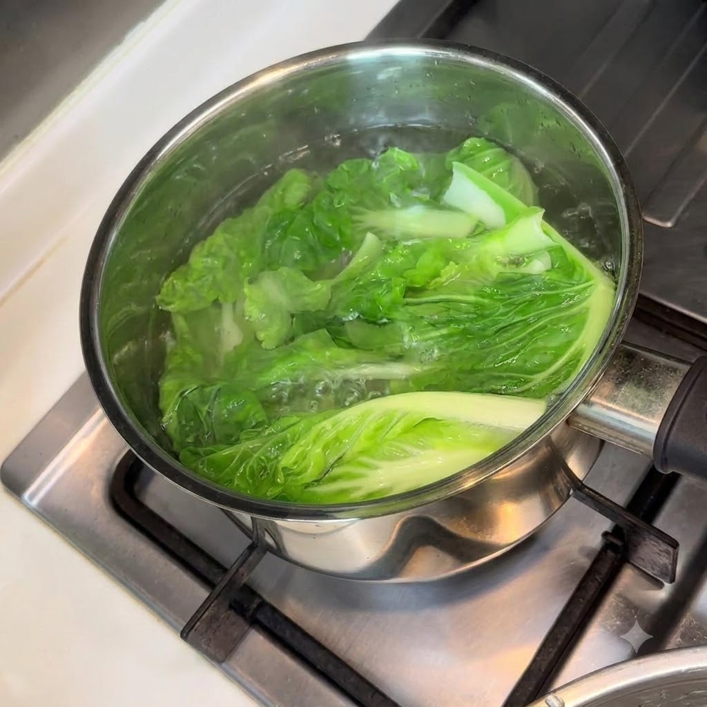 Hojas de bok choy hirviendo en una olla con agua en la estufa.