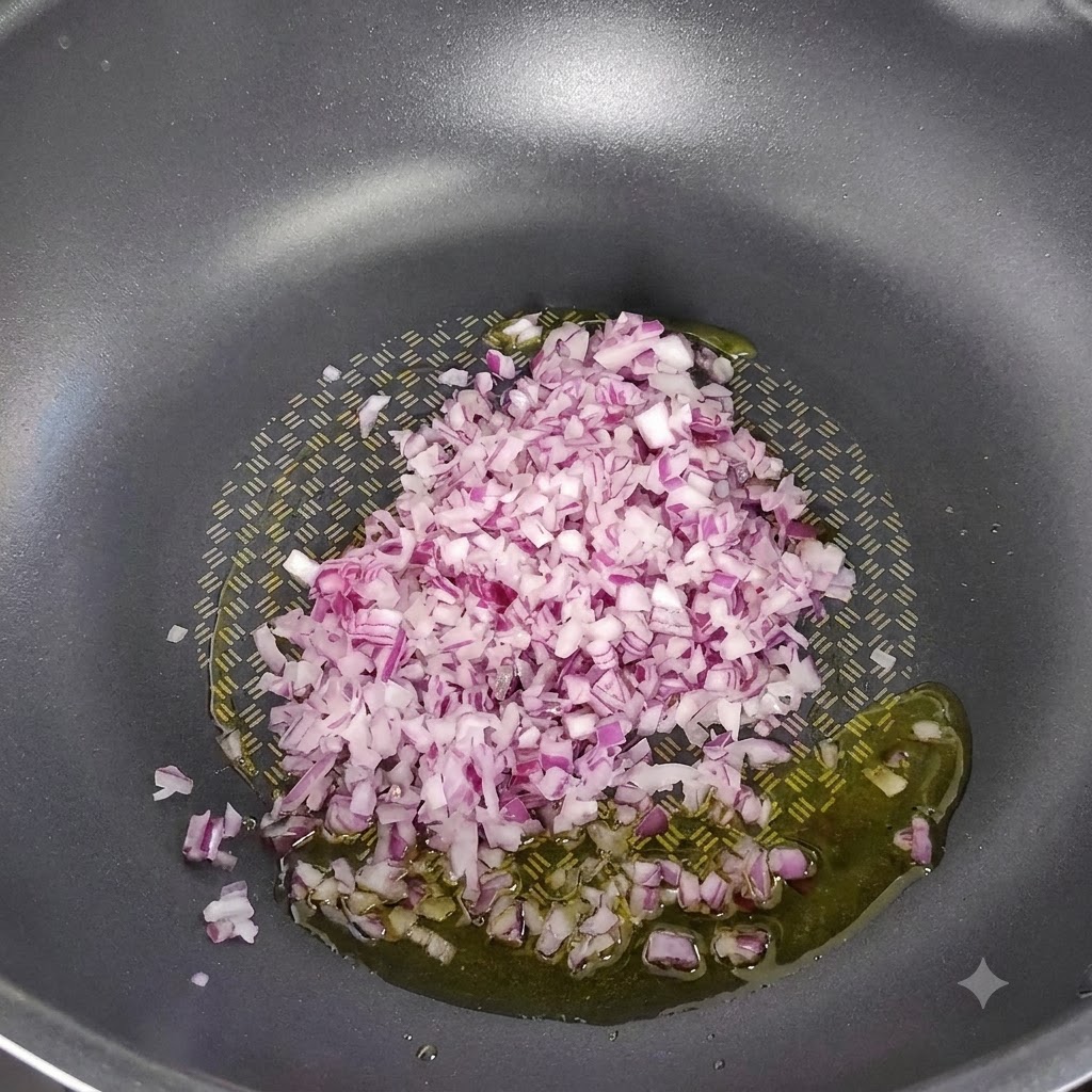 Cebolla roja picada sofriéndose en aceite de oliva en el centro de un wok antiadherente oscuro.