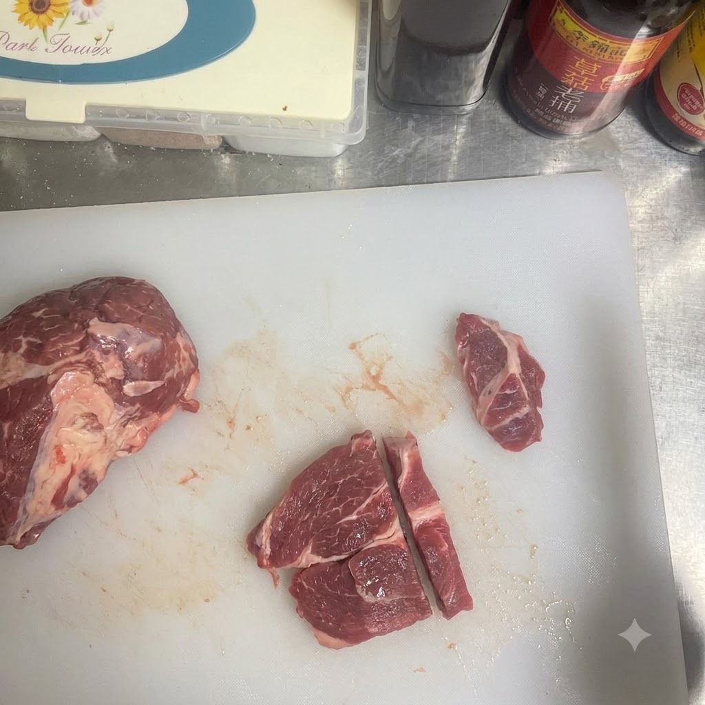 Primer plano de una persona cortando carne de res cruda en trozos pequeños sobre una tabla de cortar blanca.