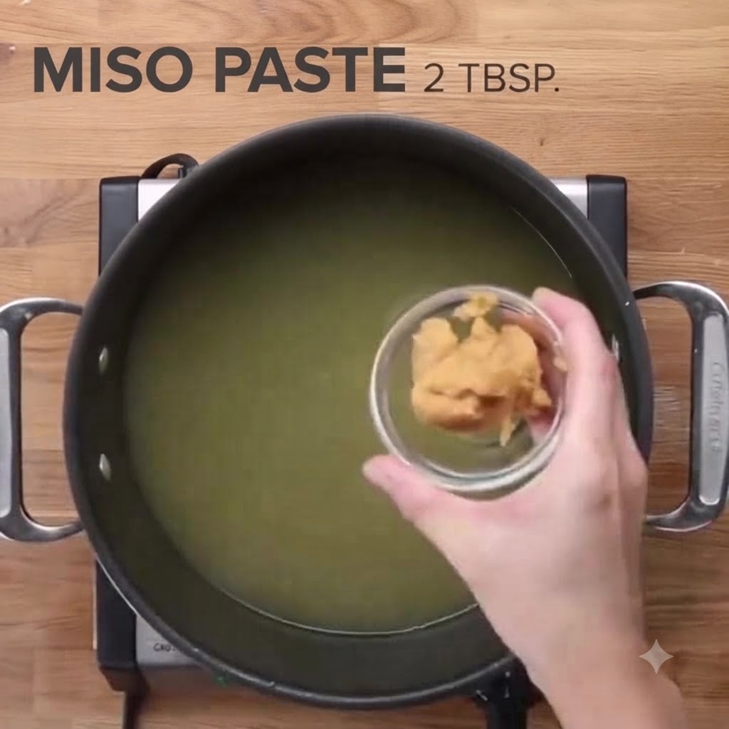Pasta de miso vertiéndose en una gran olla de caldo de pollo.